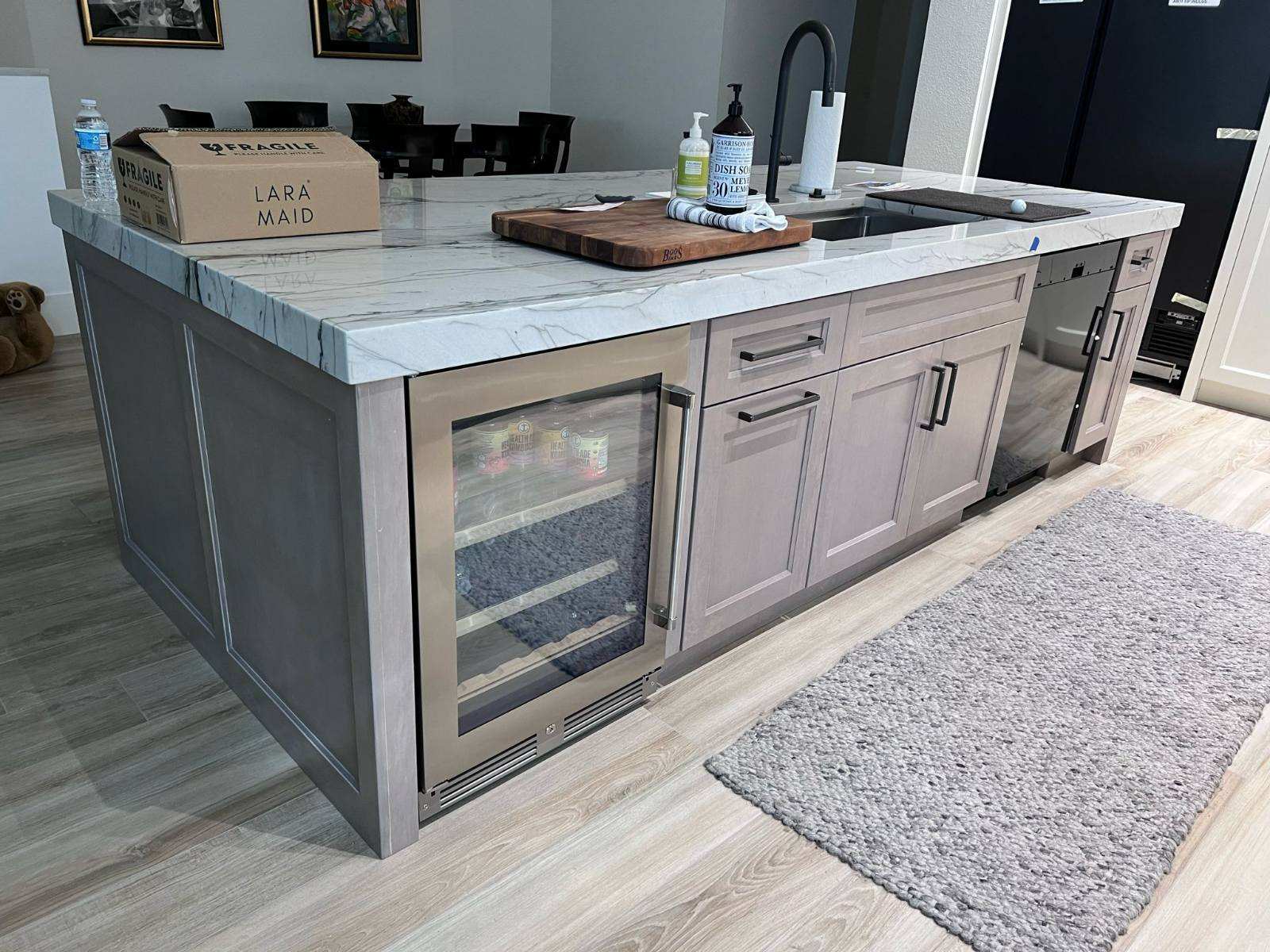 a kitchen island with a refrigerator and a wood floor