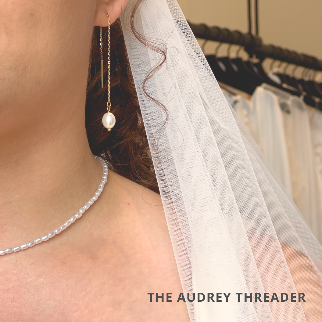 a woman wearing a white veil and a pearl necklace