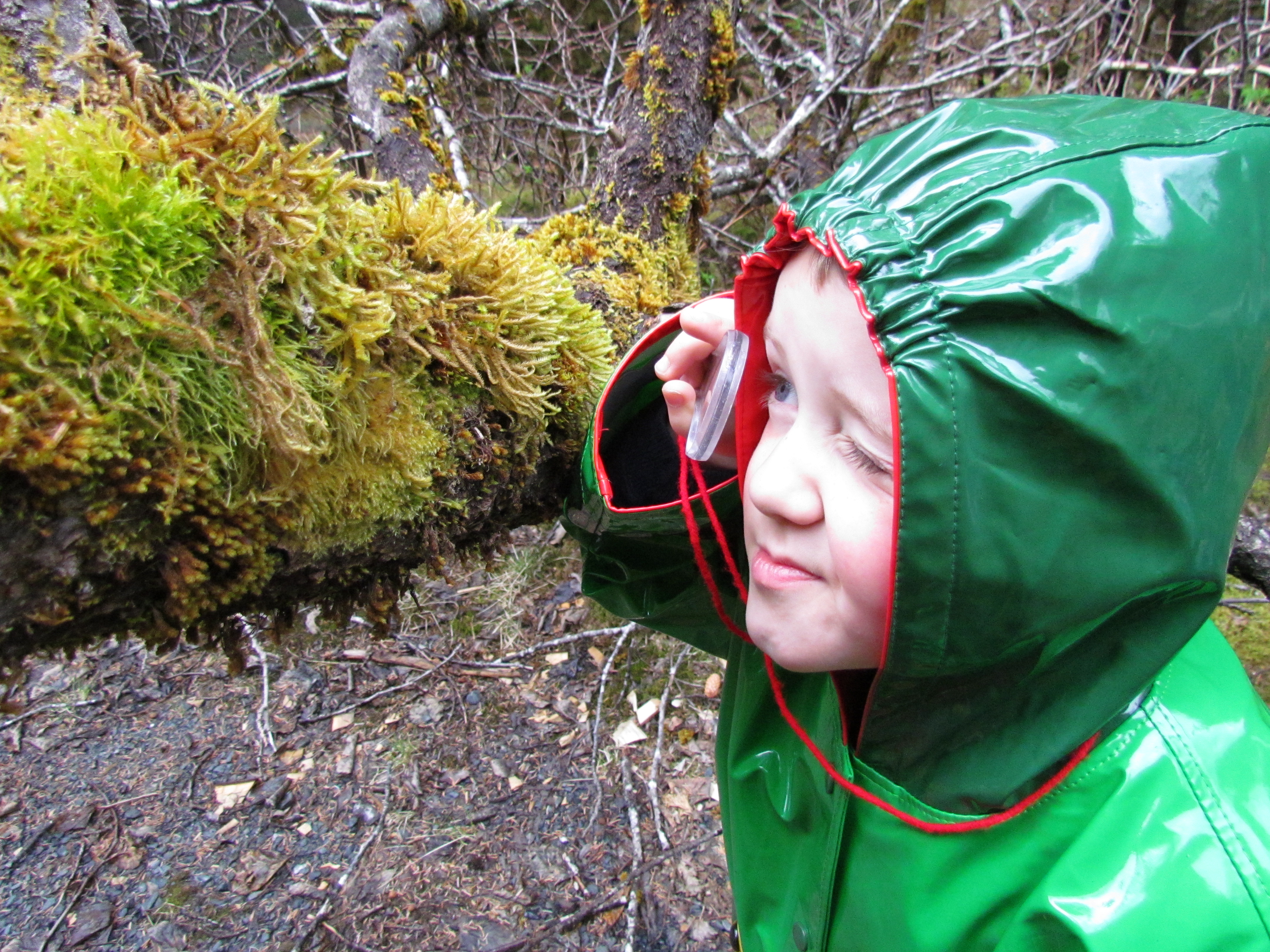 a child in a raincoat talking on a cell phone