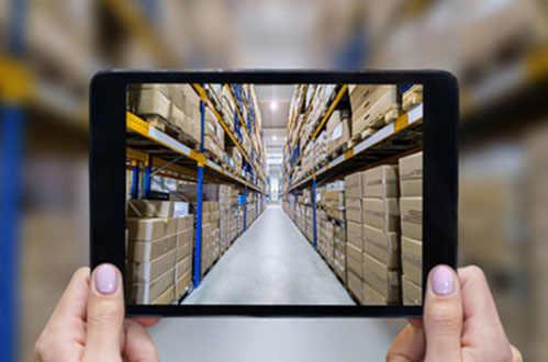 hands holding a tablet with a picture of a warehouse