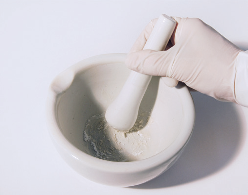 a hand in a glove holding a mortar and pestle