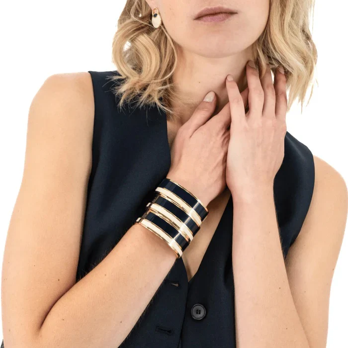 a woman with blonde hair wearing a sleeveless shirt and gold bracelets