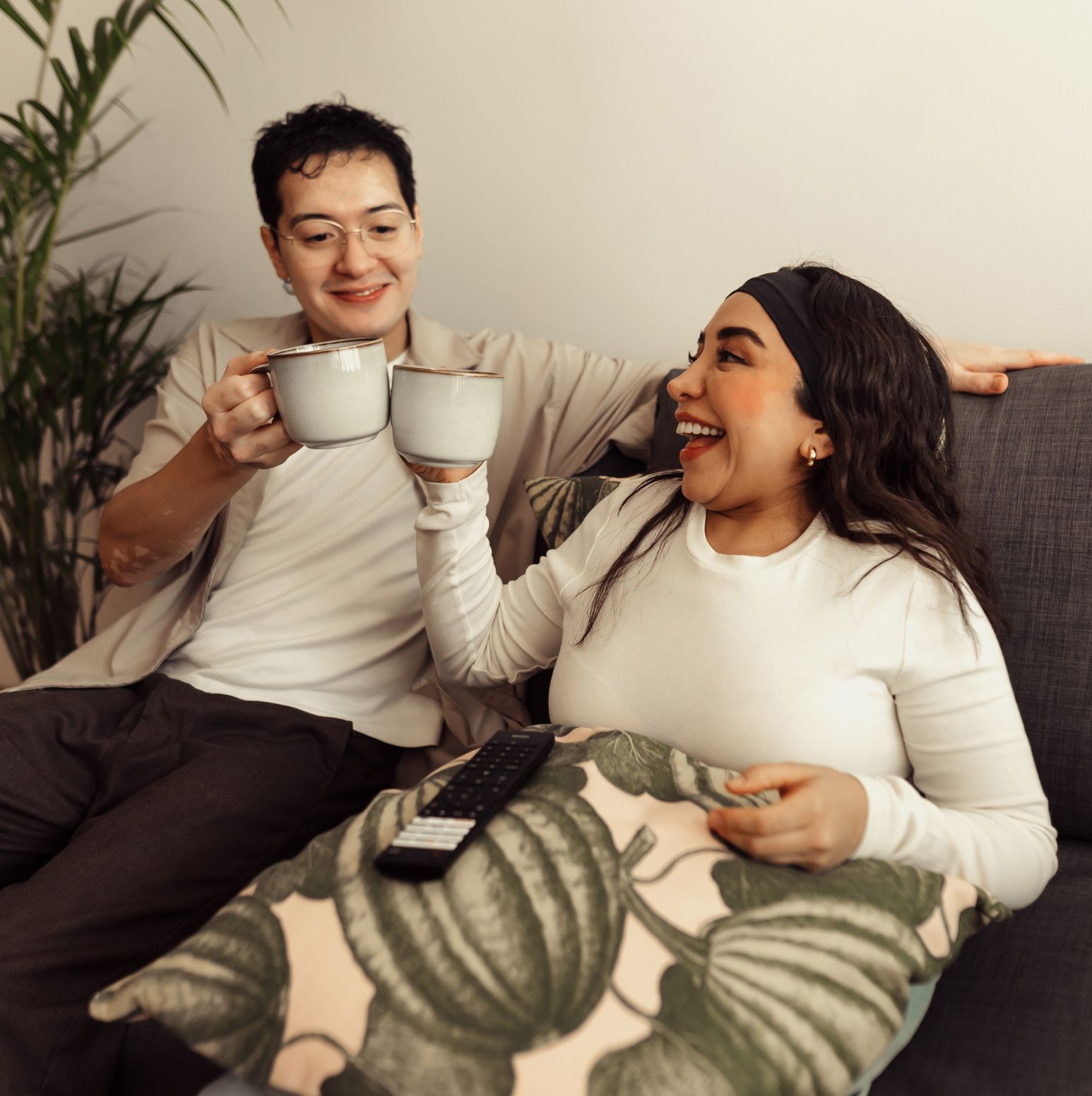 a man and woman sitting on a couch holding cups