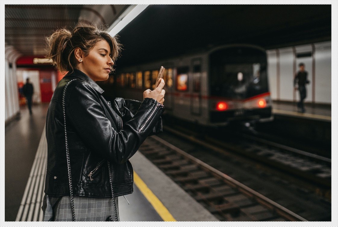 a woman standing at a train station looking at her phone