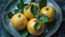 a group of yellow fruits with leaves on a blue plate