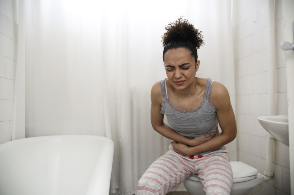 a woman sitting on a toilet with her stomach in her hands