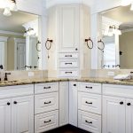 a bathroom with white cabinets and marble counter tops