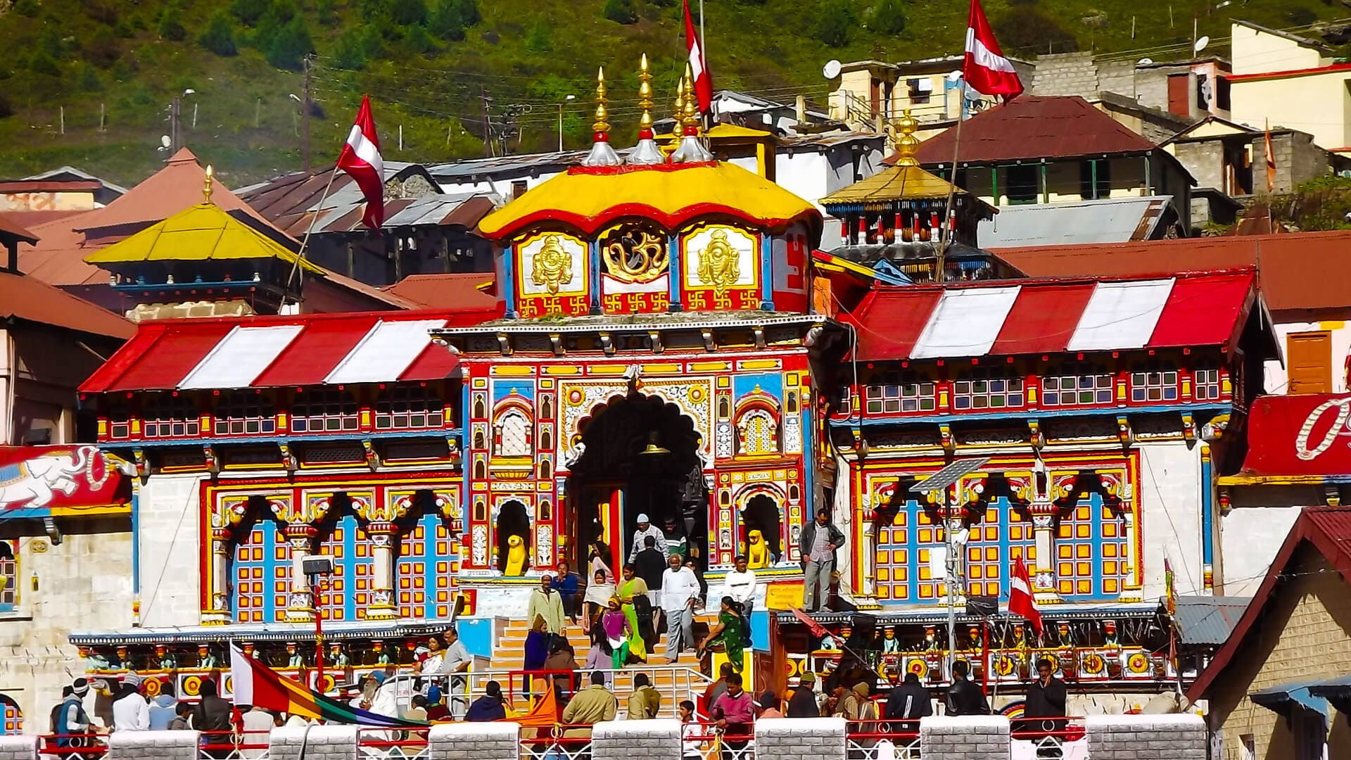 a colorful building with people in front of it with Badrinath Temple in the background