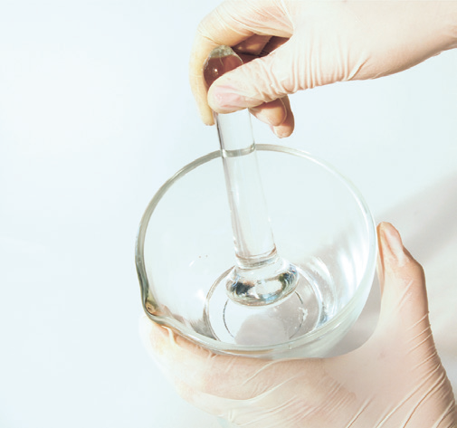 a person holding a glass beaker with a dropper