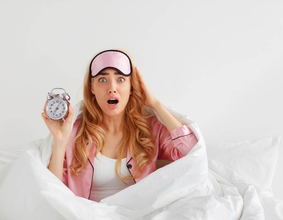 a woman in bed holding an alarm clock