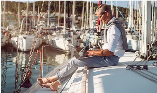 a man sitting on a boat with a laptop