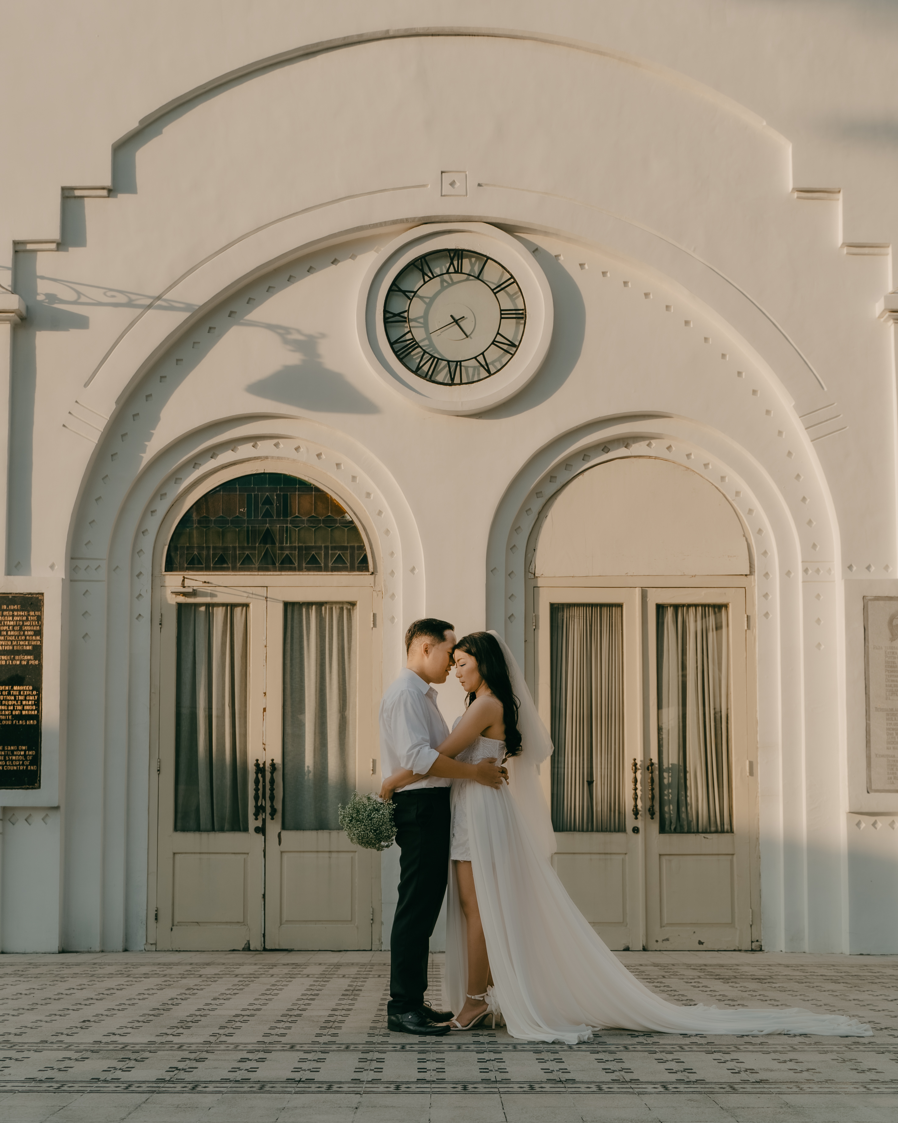 a man and woman in white dress standing in front of a building