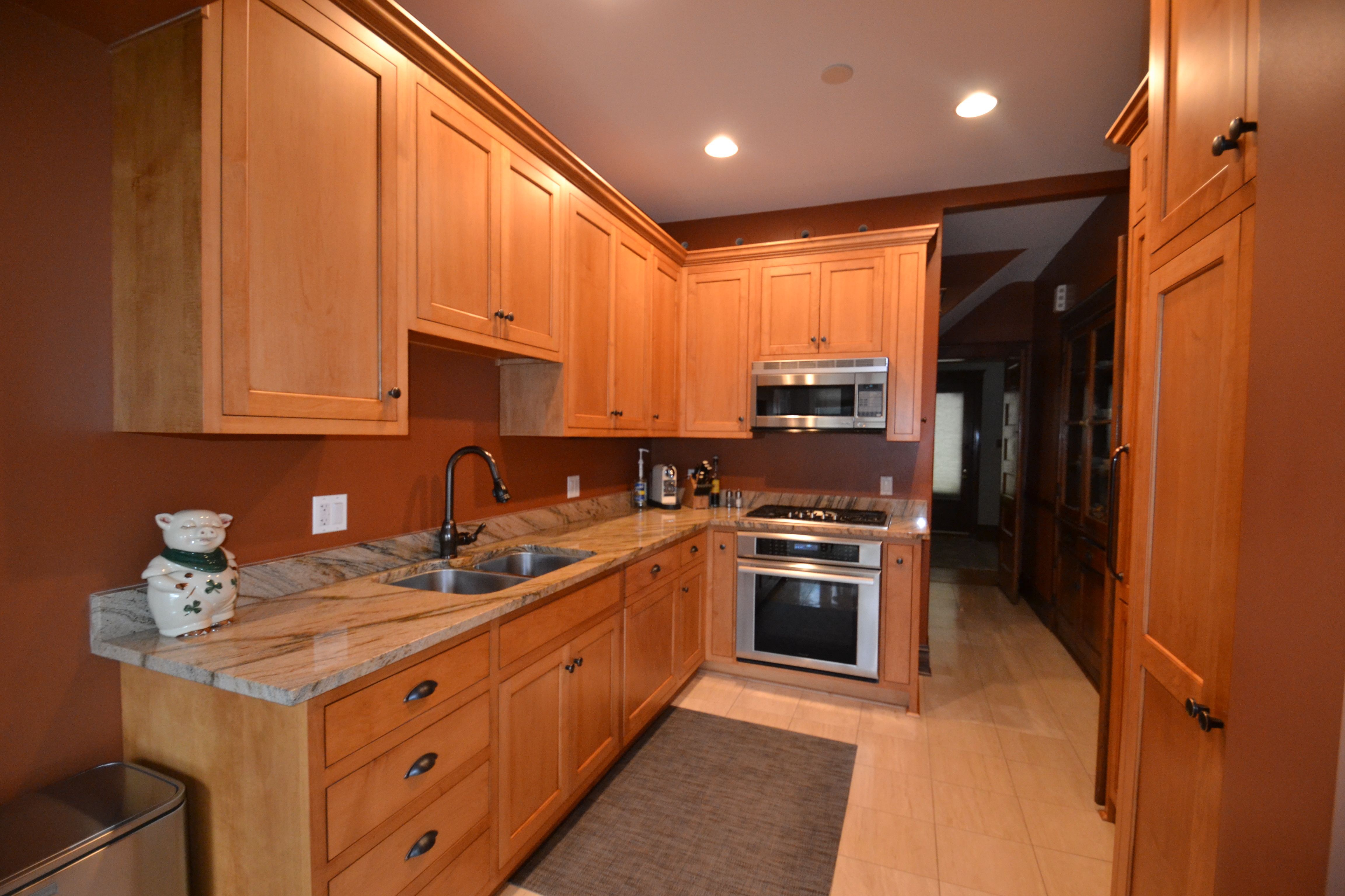 a kitchen with wooden cabinets and marble counter tops