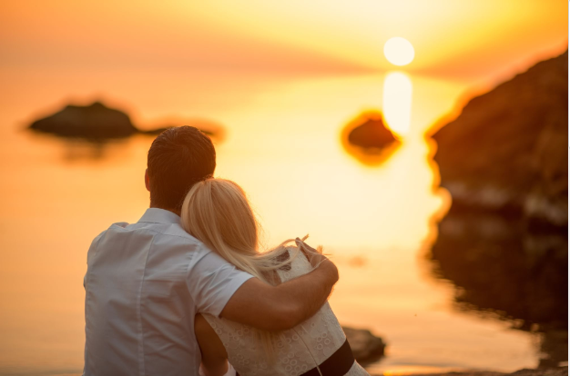 a man and woman hugging and looking at the sunset