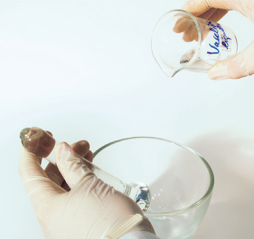 hands holding a test tube and a glass cup