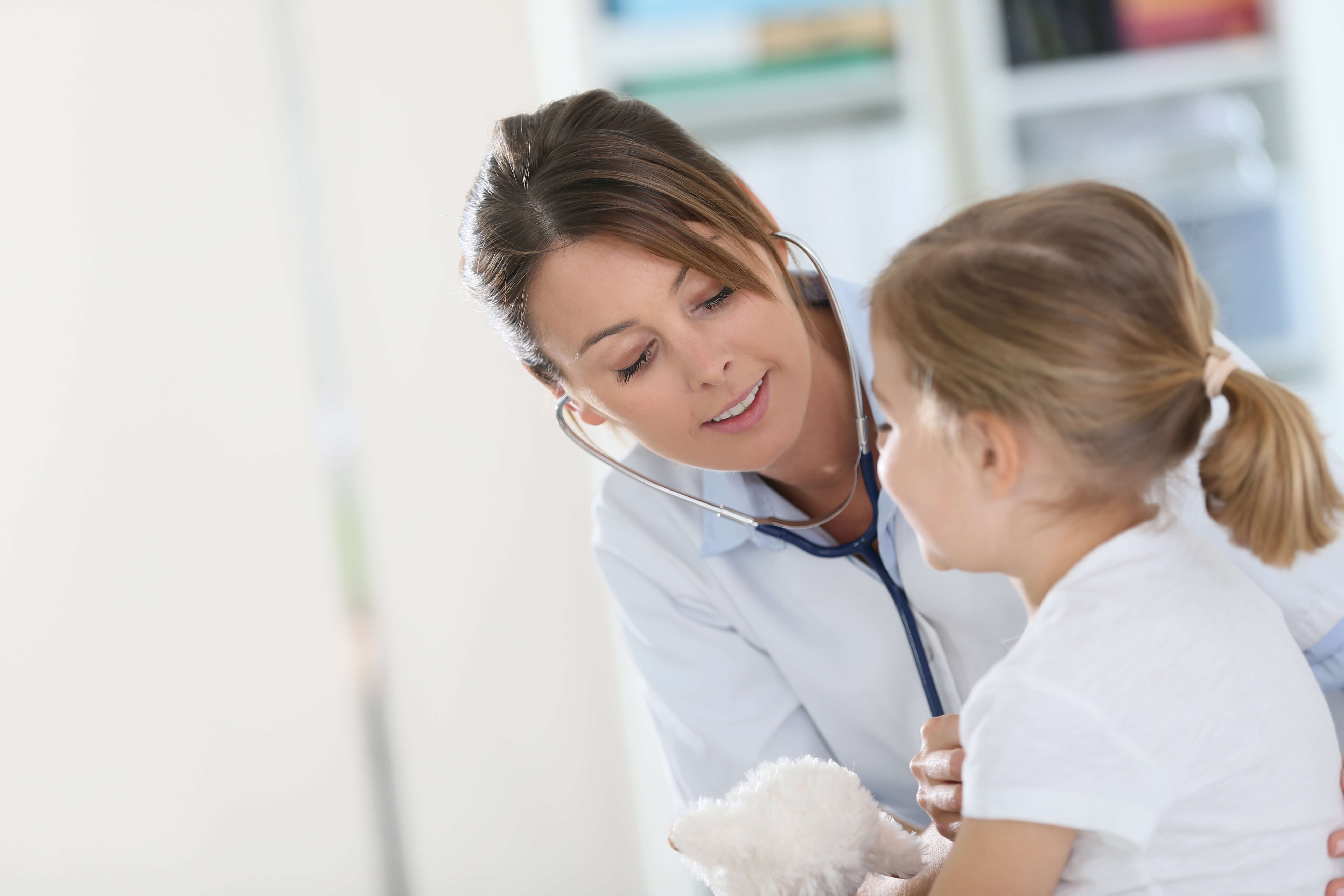 a woman with a stethoscope listening to a child's heart