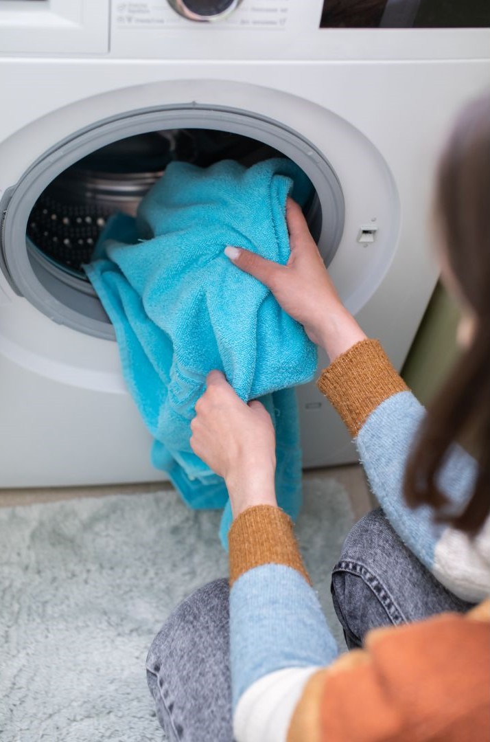 a person putting a blue towel into a washing machine