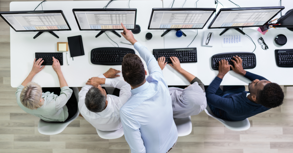 a group of people sitting at a desk using computers