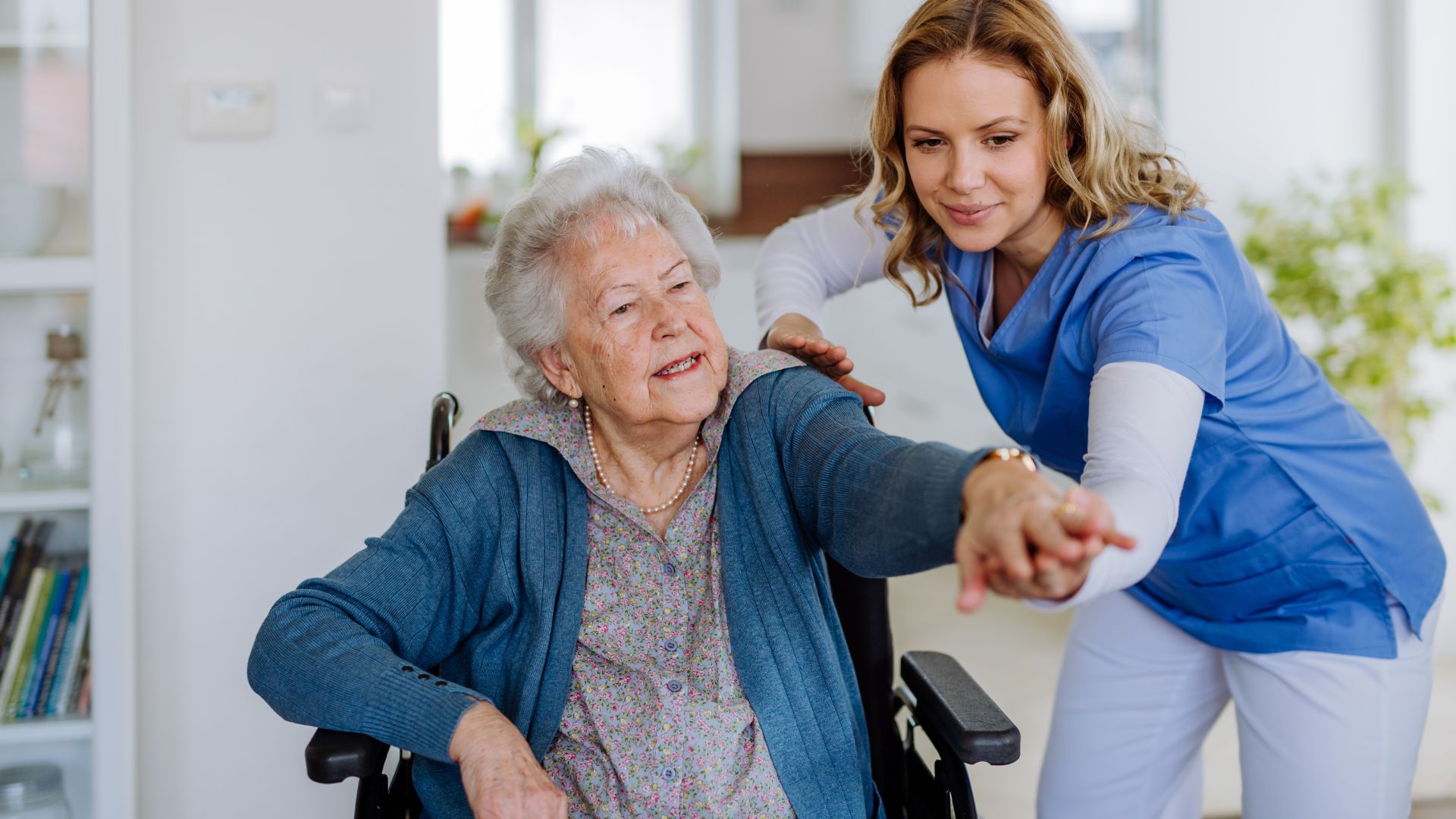 a woman in a wheelchair with a nurse touching her hand