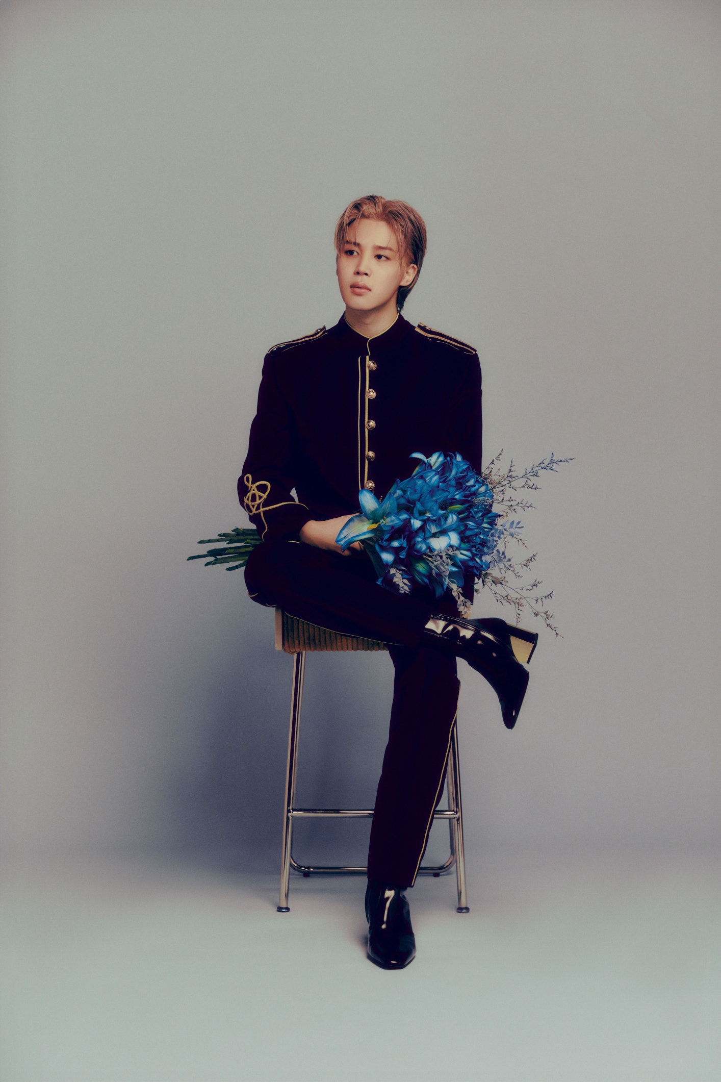 a man sitting on a stool holding flowers