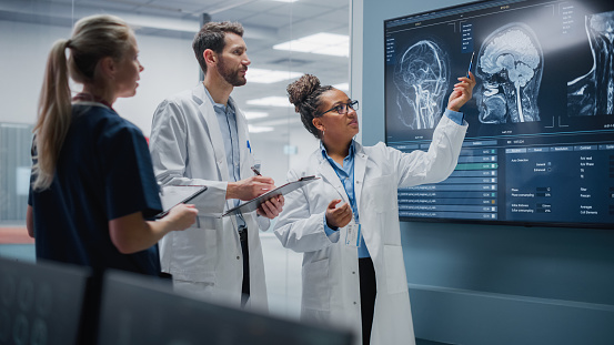 a group of people in lab coats looking at a large screen