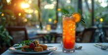 a glass of orange liquid next to a plate of food