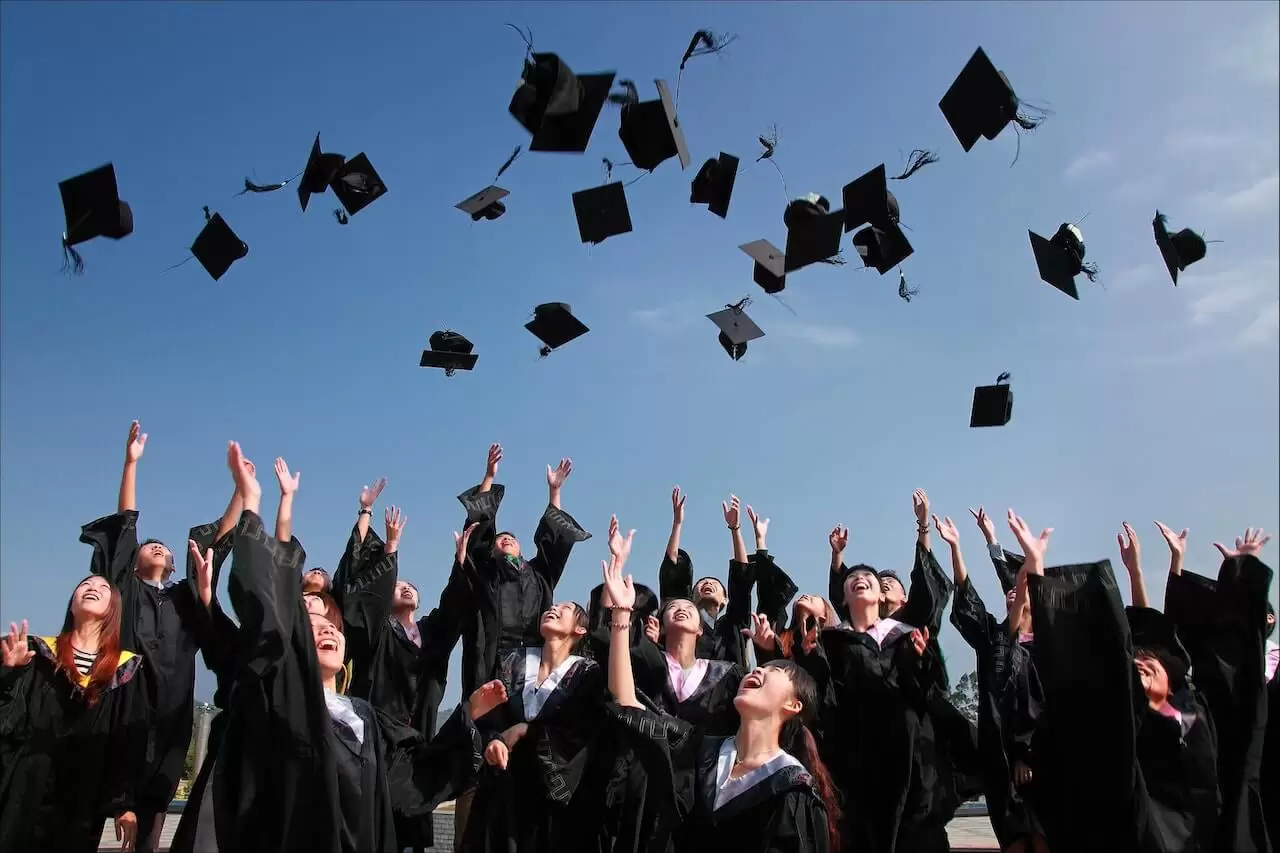 a group of people in graduation gowns throwing their caps in the air