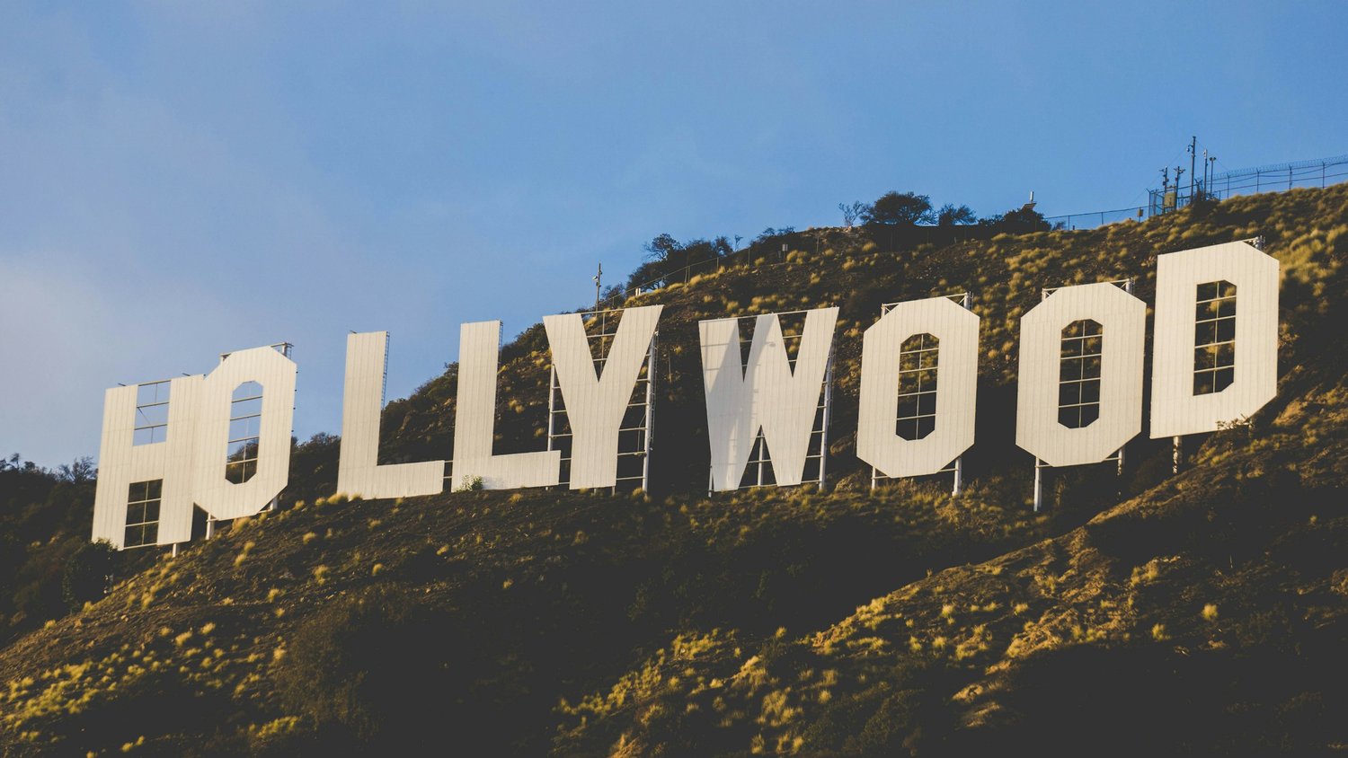 a large white sign on a hill with Hollywood Sign in the background