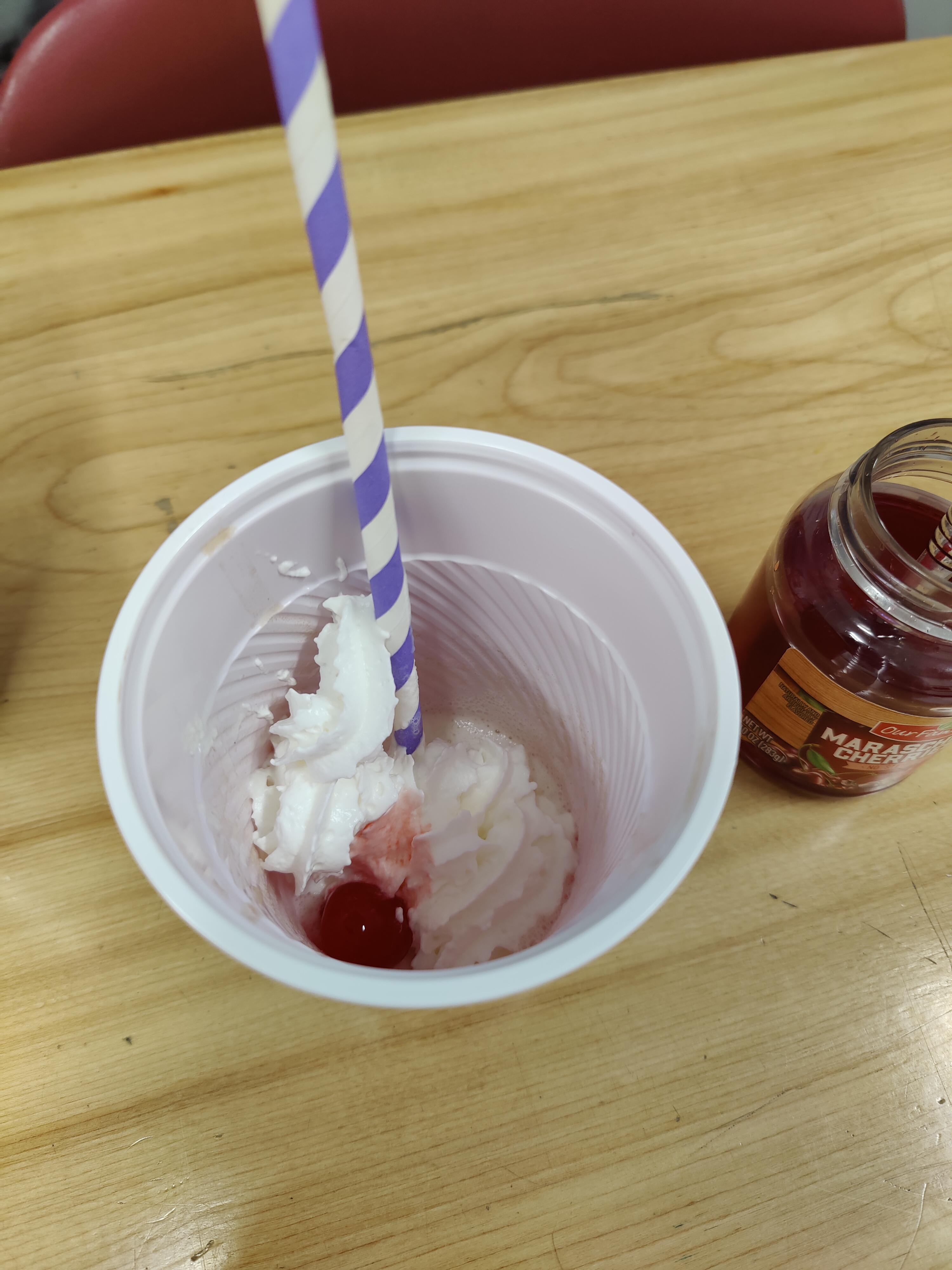 a cup of ice cream with a straw and a cherry in it