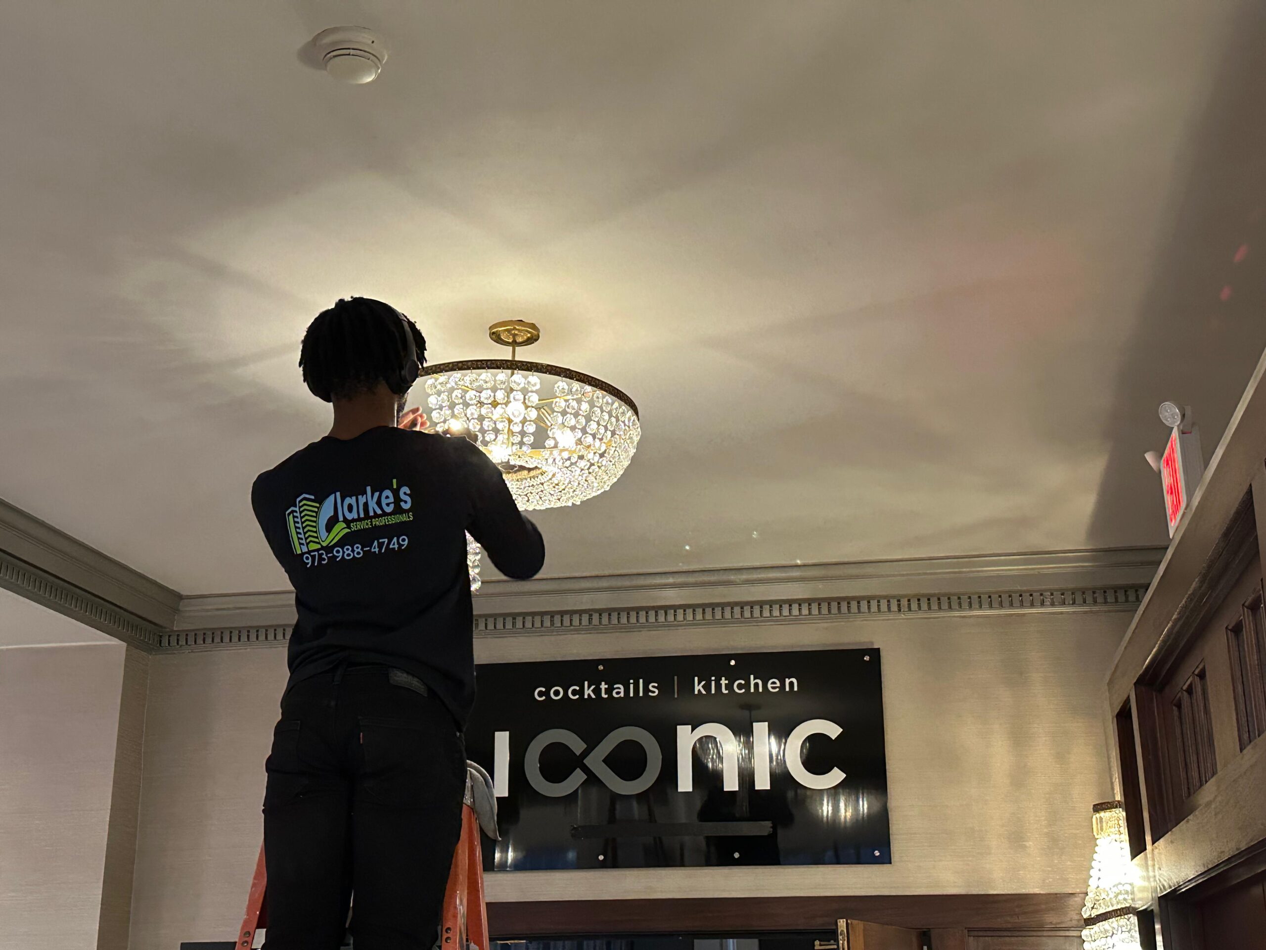 a man standing on a ladder holding a chandelier