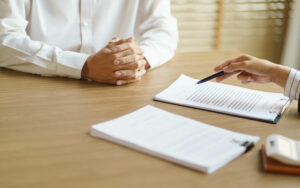 a person sitting at a table with a pen and papers