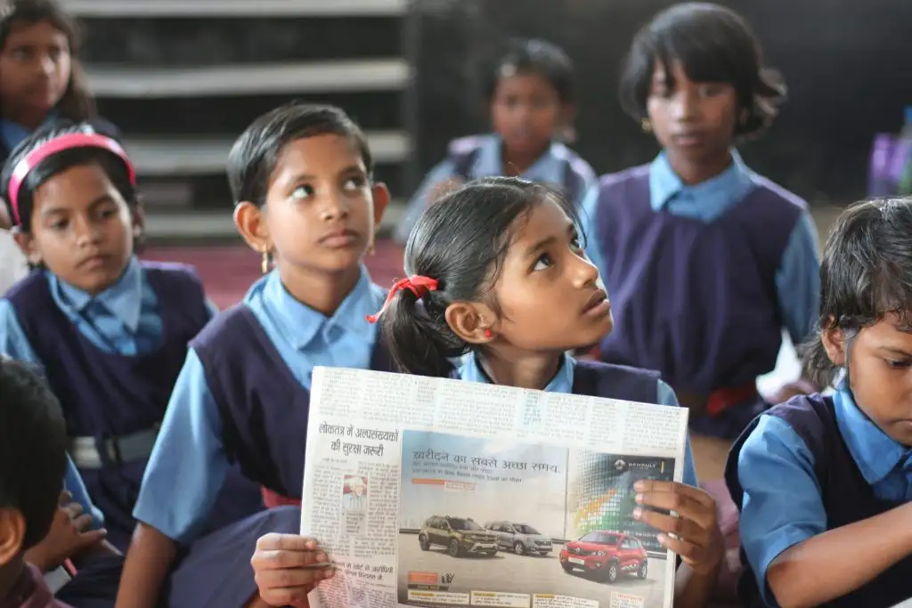 a group of girls in uniform reading a newspaper