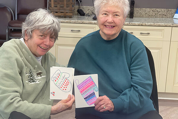 two women holding cards with christmas decorations