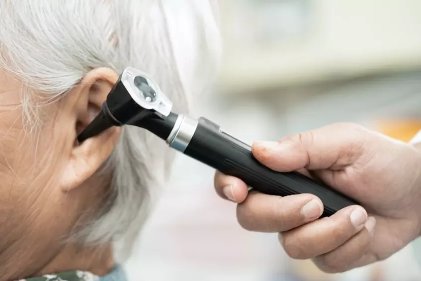 a doctor using a otoscope to check the ear of a woman