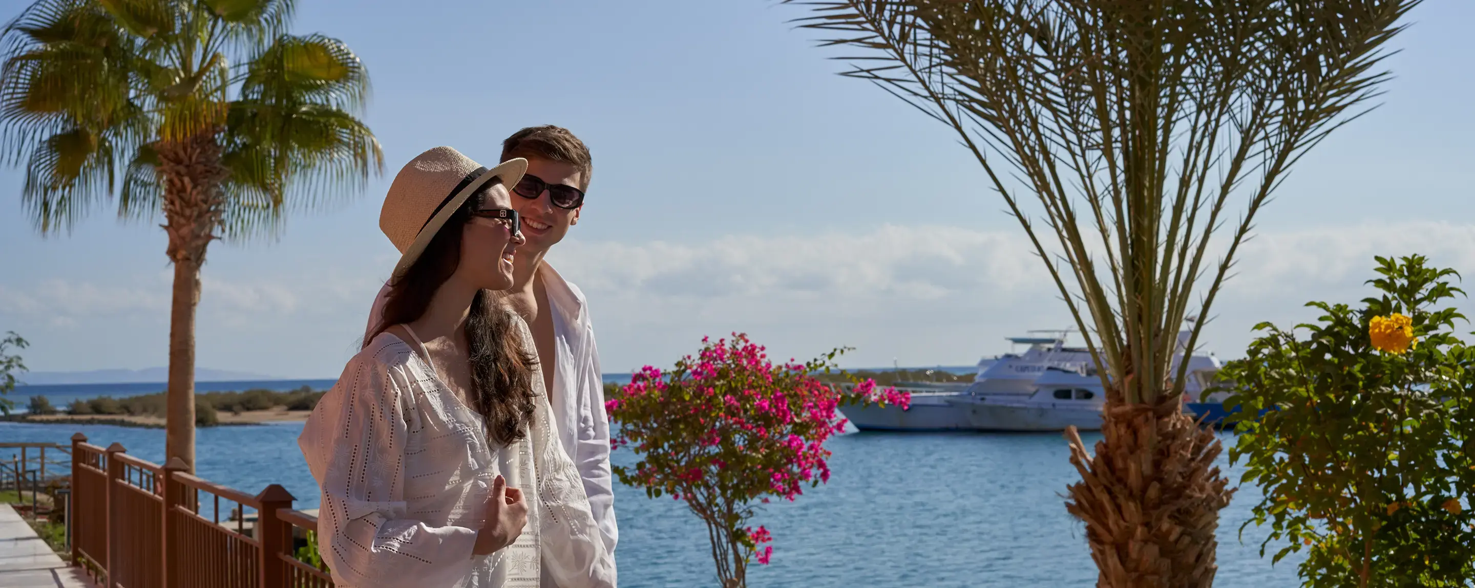 a man and woman standing next to a palm tree