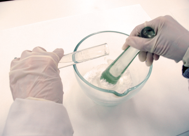 a person pouring liquid into a glass bowl