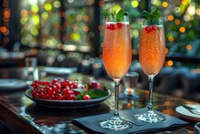 two glasses of orange liquid with berries on a table