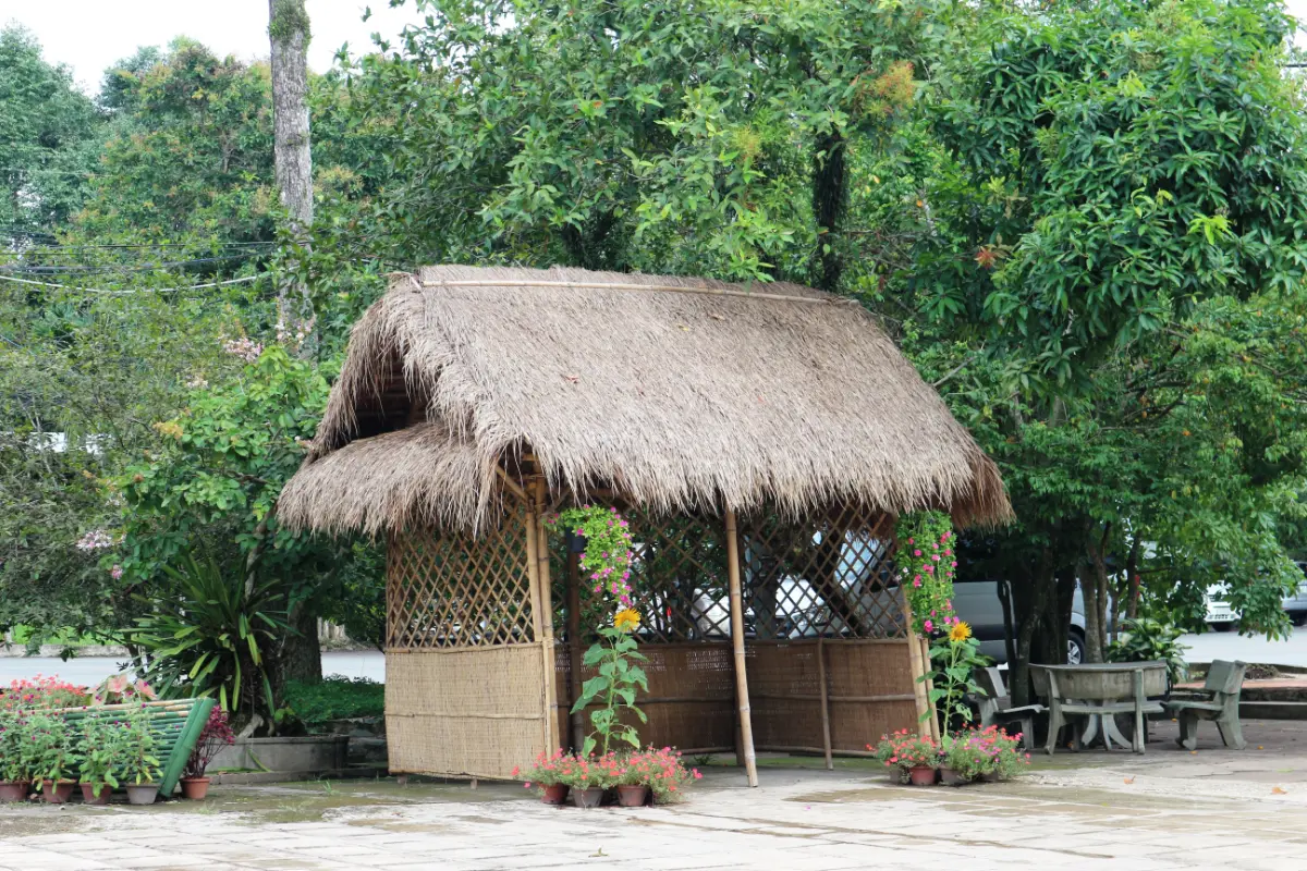 a straw hut with flowers and trees