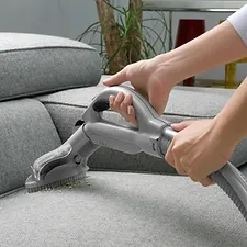 a person vacuuming a couch