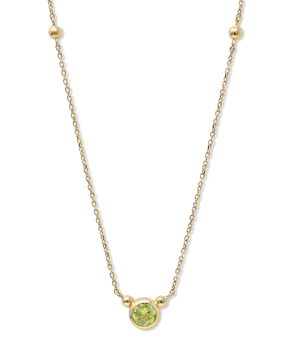 a gold necklace with a green stone