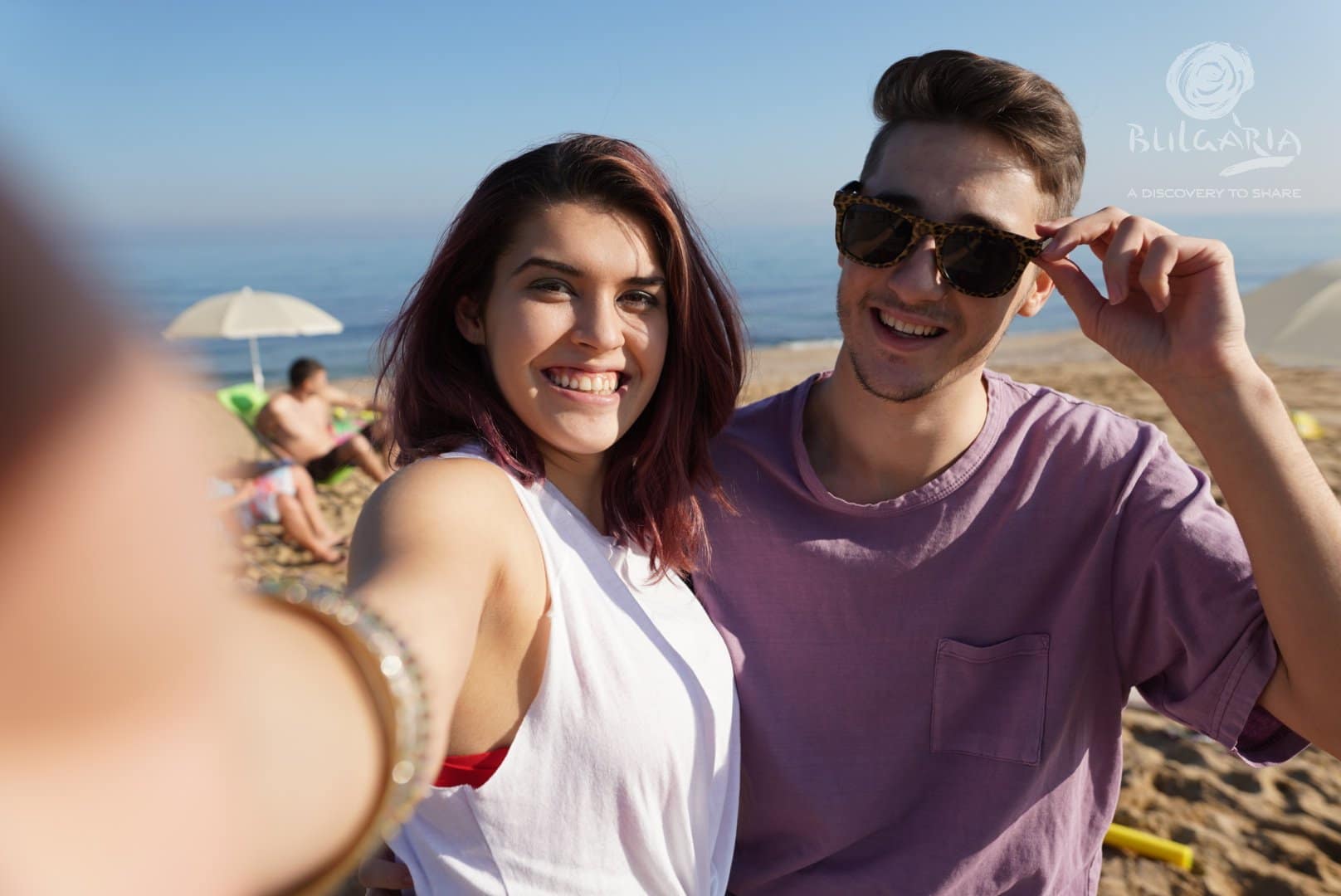 a man and woman taking a selfie at the beach