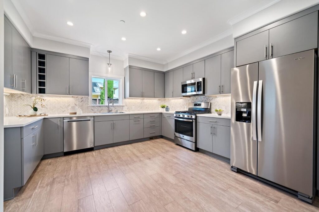 a kitchen with grey cabinets and stainless steel appliances