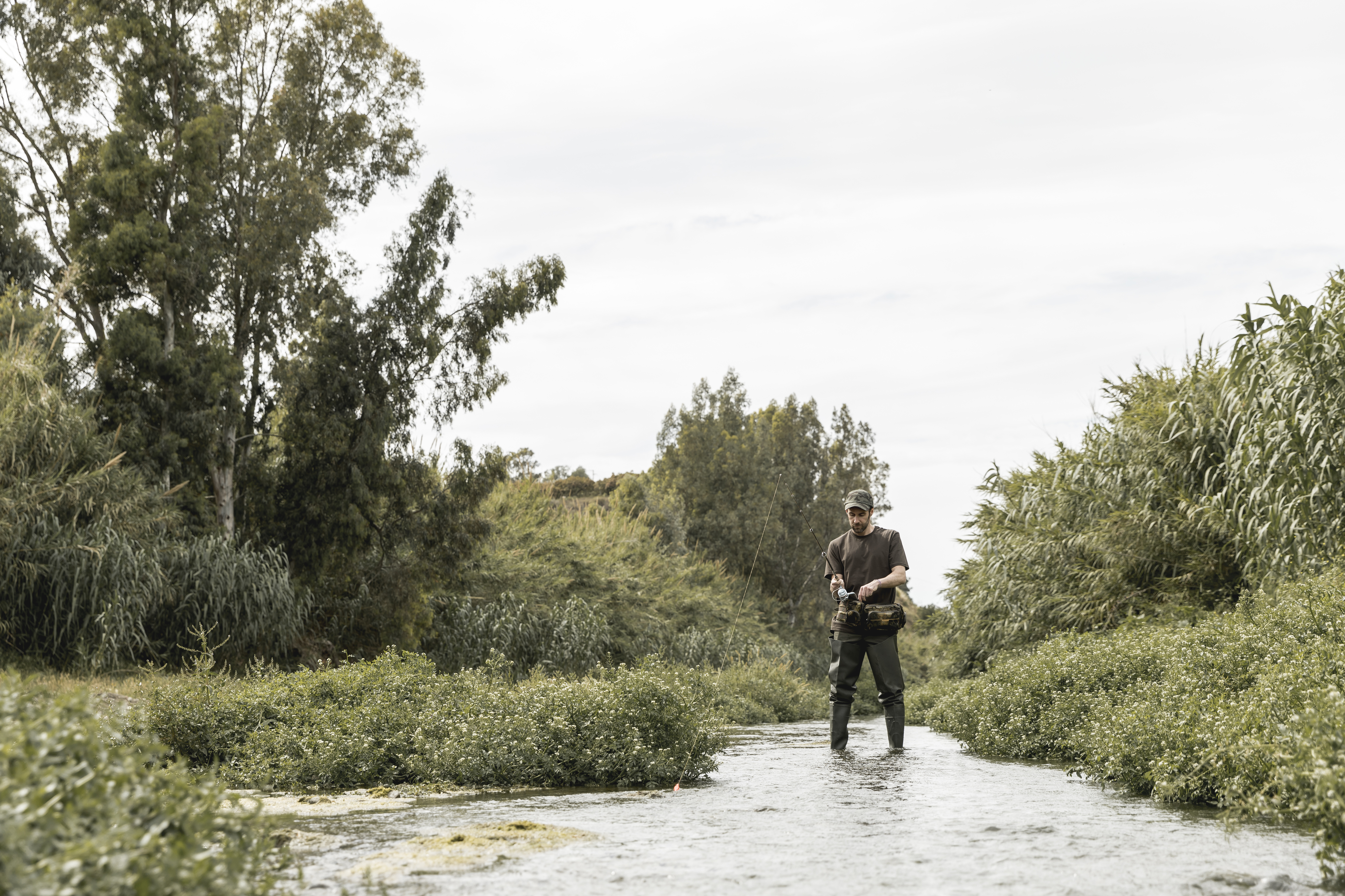 a man standing in a river with a fishing pole