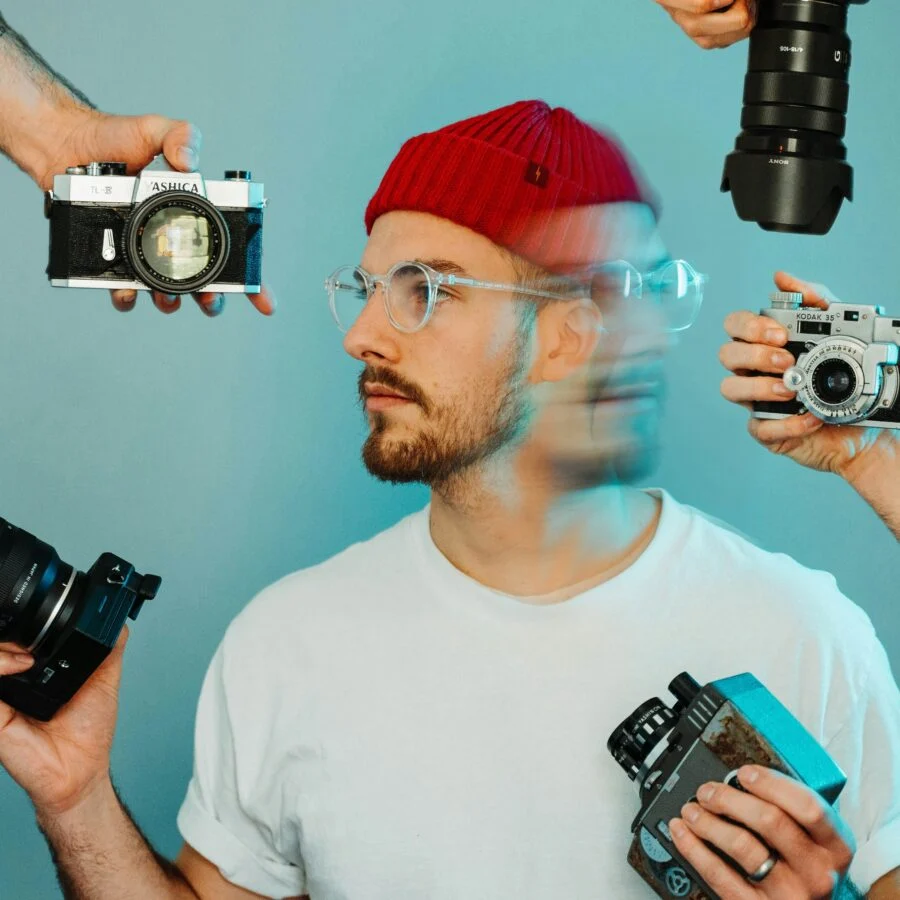 a man holding several cameras