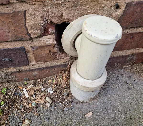a white pipe in a brick wall