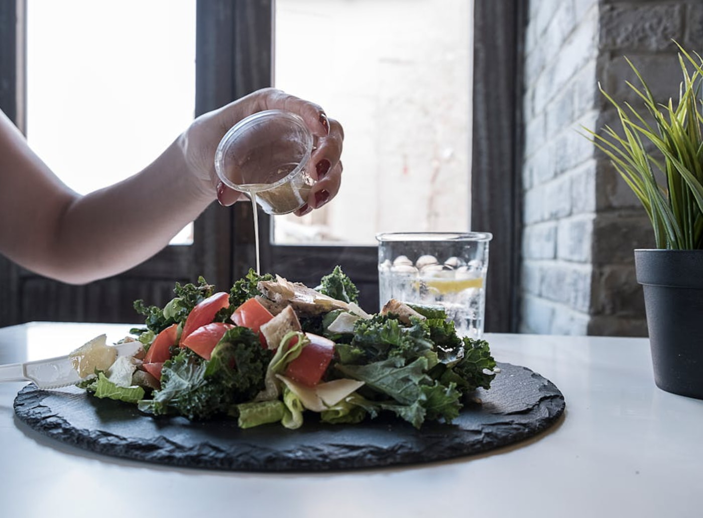 a person pouring a dressing on a salad