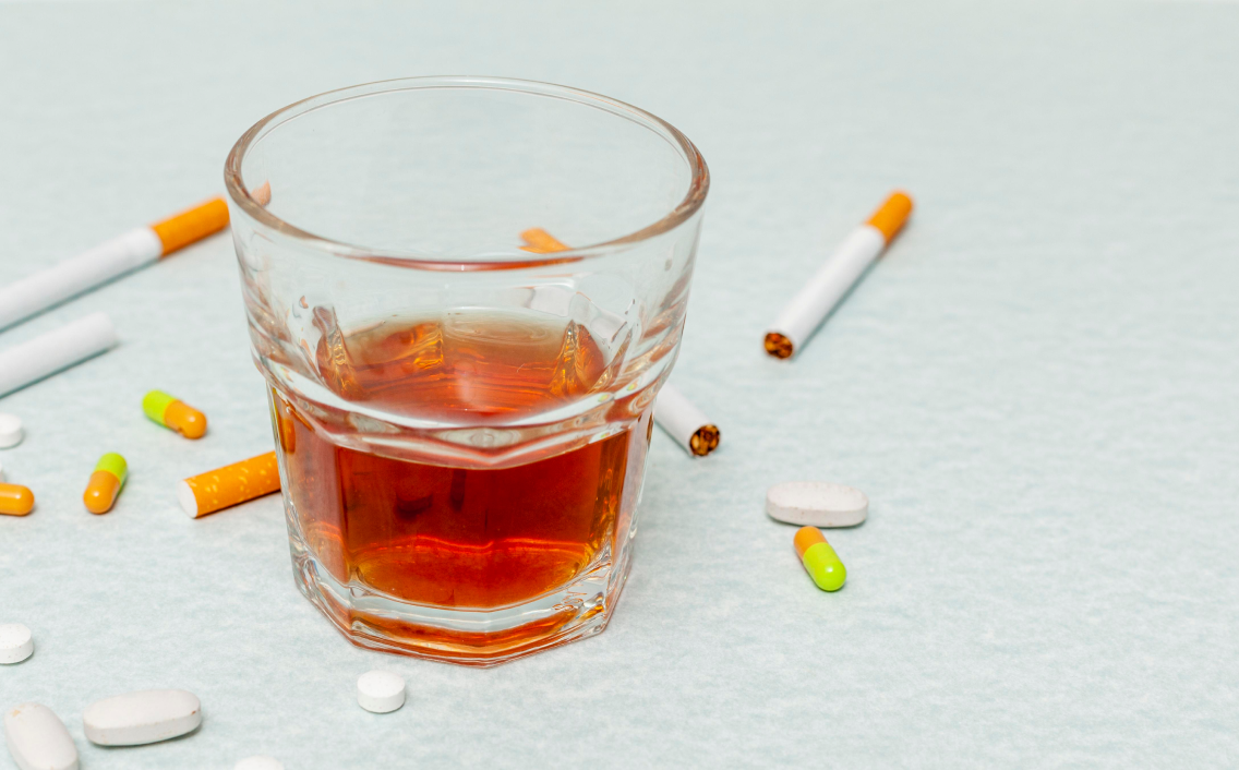 a glass of alcohol next to cigarettes and cigarettes