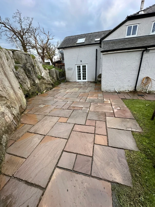 a stone patio with a stone wall and a house