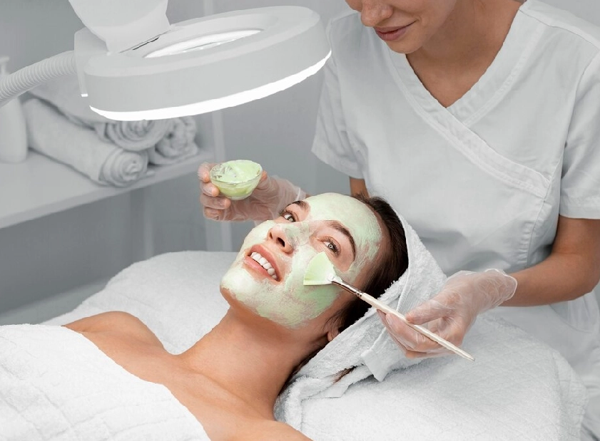 a woman getting a green facial mask