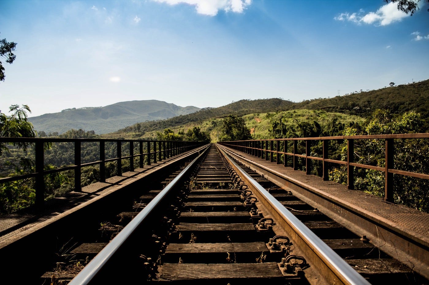 a train tracks with trees and mountains in the background